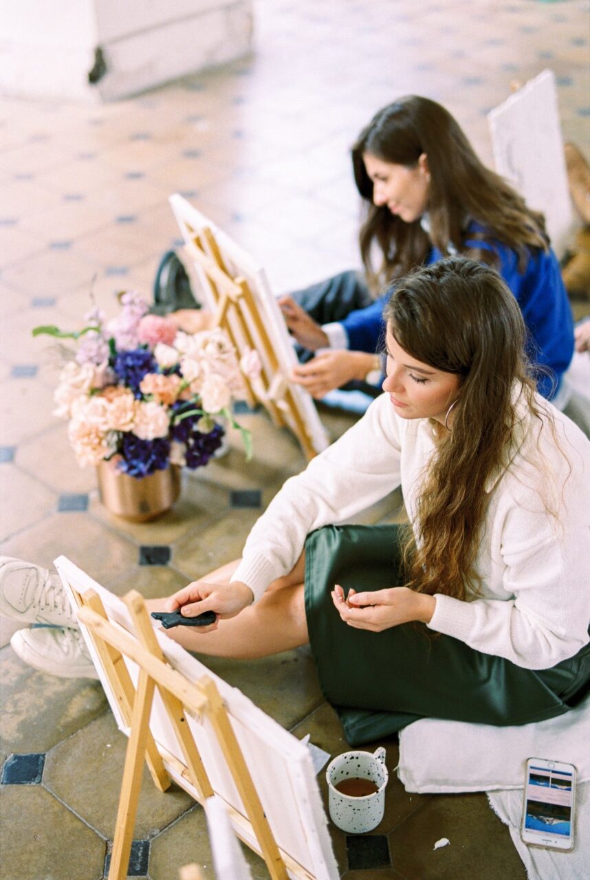 Dos mujeres creando pinturas sobre lienzo durante un taller