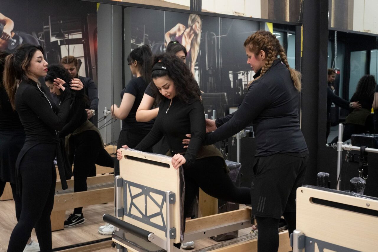 Profesional guiando a varias mujeres durante una sesión de Pilates con máquinas