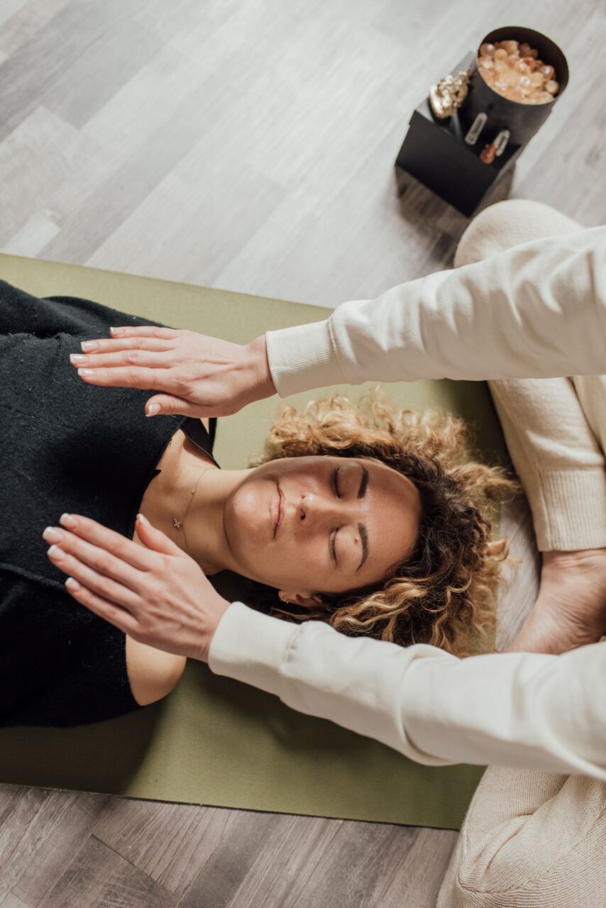 Persona recibiendo una sesión de Reiki con las manos de la profesional sobre el cuerpo