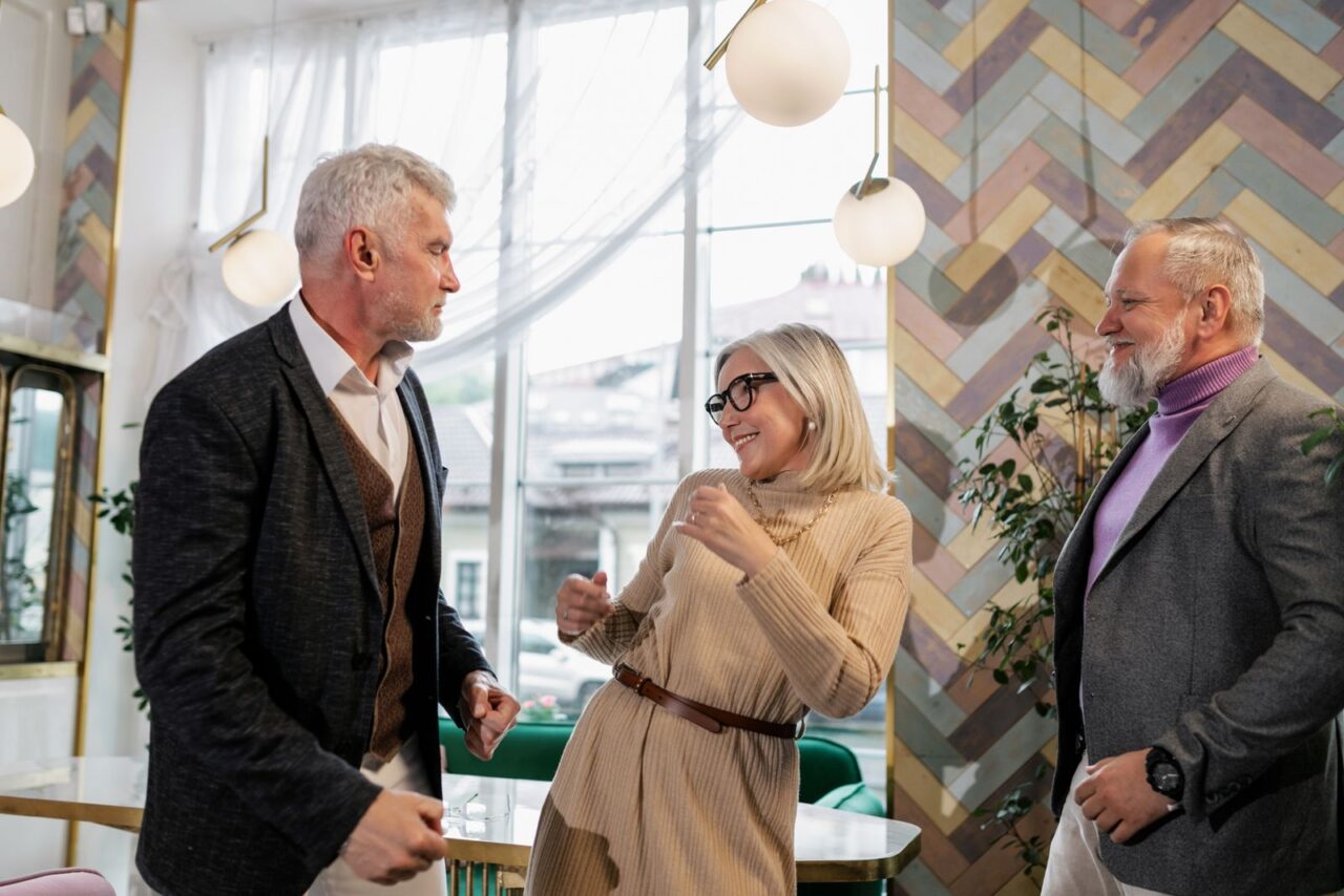Tres personas mayores compartiendo una conversación alegre en grupo