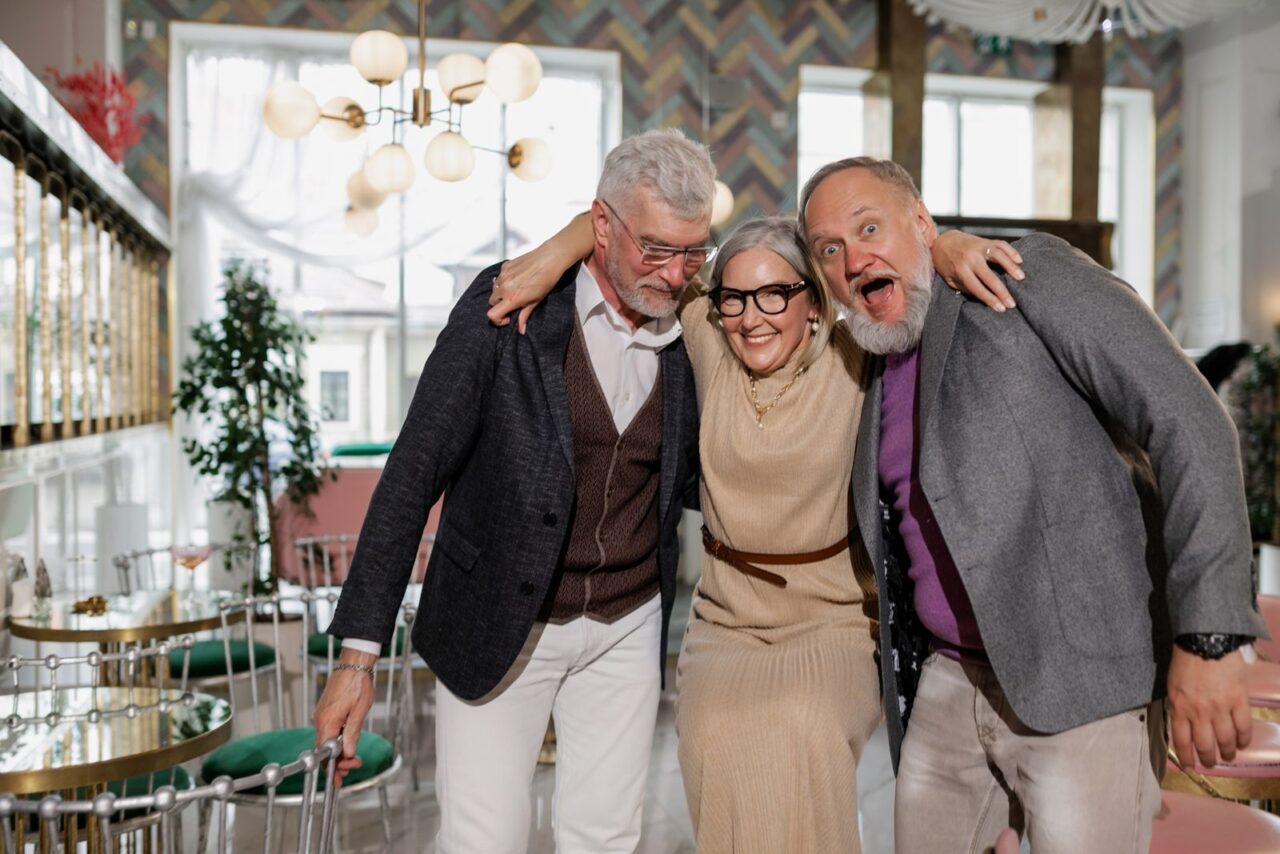 Tres personas mayores abrazadas y sonriendo durante una actividad social