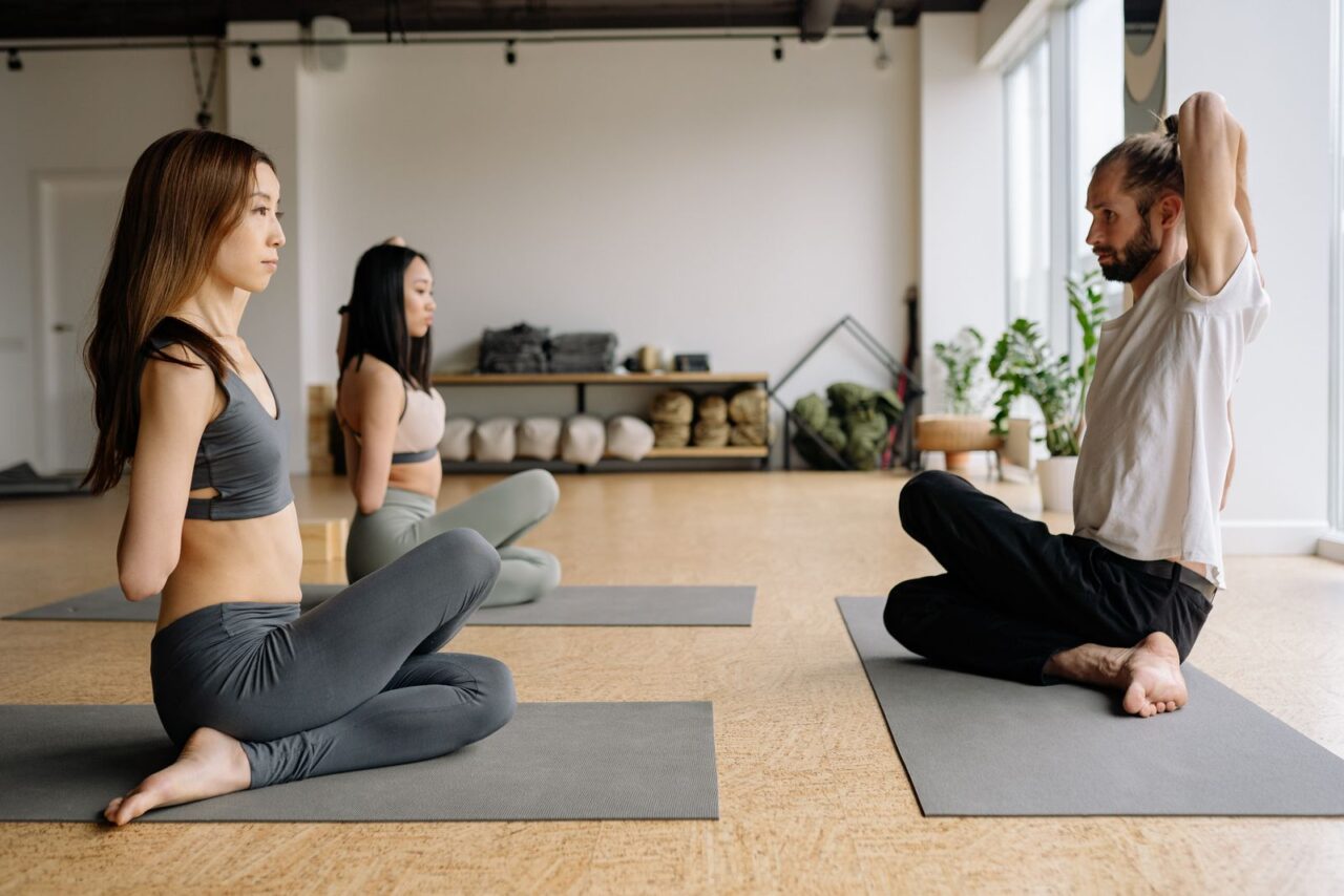 Personas siguiendo una práctica de yoga guiada en una sala luminosa